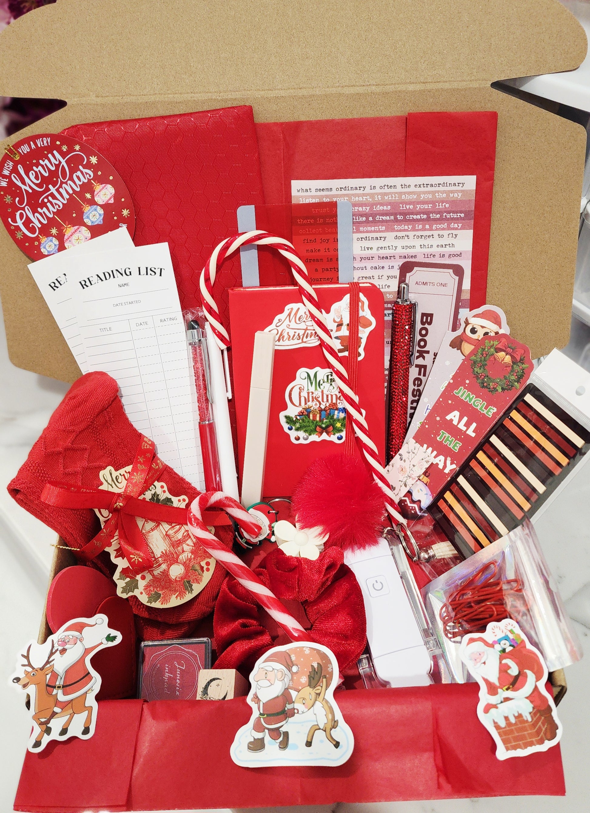 Christmas-themed gift box with stationery items and festive decorations.